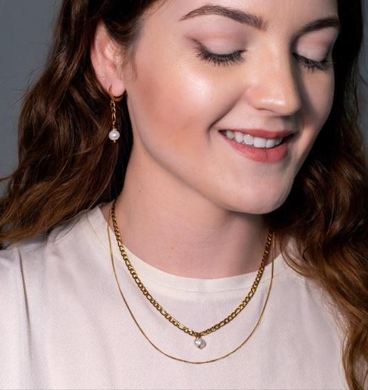 The Drop Necklace elegantly layers 18K gold chains with a stunning freshwater pearl, perfect for daily wear.