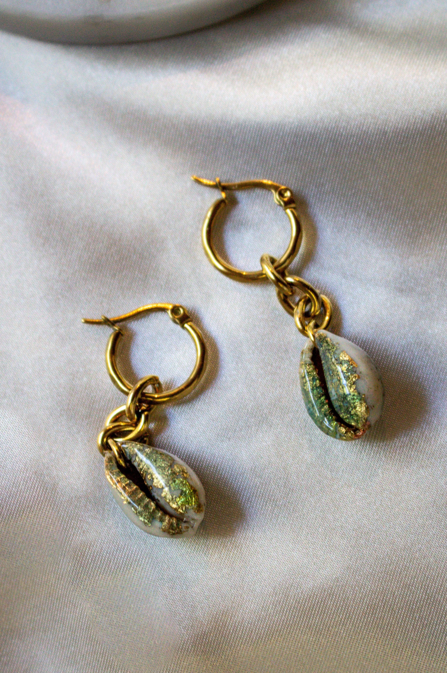 Chunky Gilded Drops earrings showcase hand-gilded cowrie shells with a shimmering gold and sea-green finish.