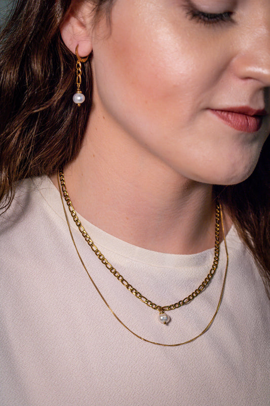 The Drop Necklace features elegant 18K gold chains and a stunning freshwater pearl, perfect for any occasion.